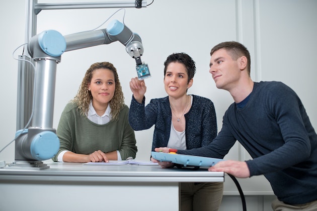 Zwei Studenten mit einer Dozentin an einem technischen Gerät, als Symbolbild für Hochschule Heilbronn